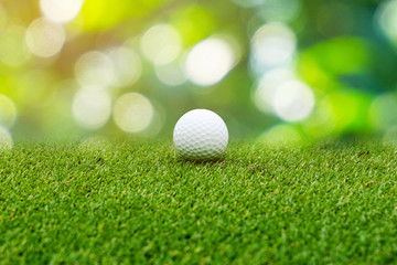 White Golf ball on green course to be shot on green light bokeh of golf course in bright day time...