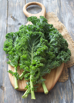 Fresh green curly kale leaves on a cutting board on a wooden table. selective focus. rustic style. healthy vegetarian food
