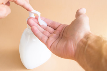 Liquid soap bottle and pressing on the dispenser, soap on the palm. Washing hands.