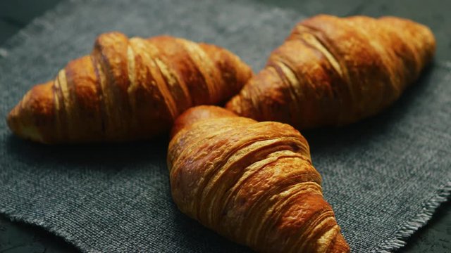 From above view of three fresh croissants laid on textile napkin 