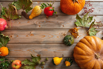 Thanksgiving flat lay with colorful pumpkins, fruits and fall leaves on rustic wooden background, copy space