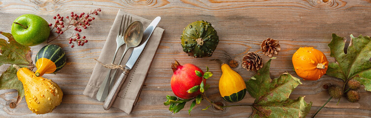 Thanksgiving flat lay with colorful pumpkins and place setting on rustic wooden table, banner, top view