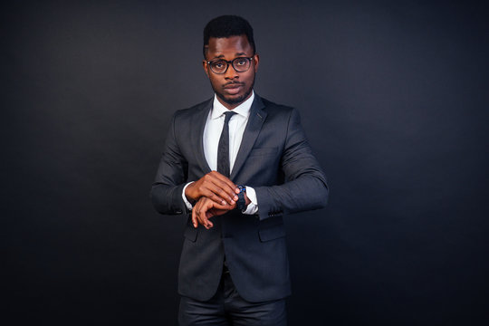 handsome black successful and clever american student with glasses in the University in dark suit. Studio fashion shot isolated on black background.
