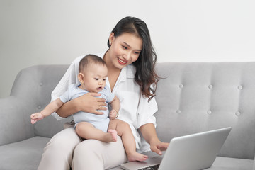Happy family mother and baby at home using laptop computer