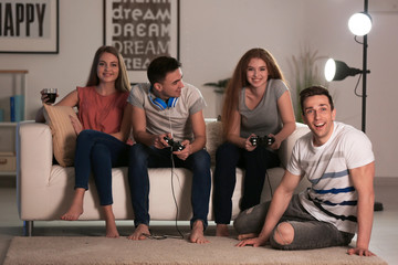 Young people playing video games at home in evening