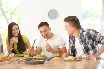 Friends eating at table in kitchen