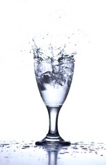 ice cubes splashing in clear water glass