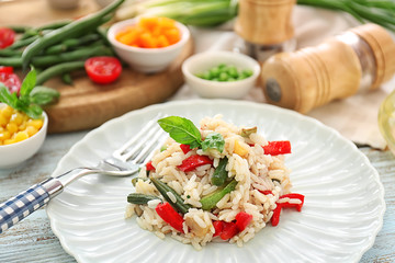 Plate with tasty boiled rice and vegetables on wooden table