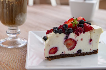 cheesecake with fresh fruit and iced coffee in the background