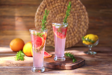 Fresh grapefruit cocktail with rosemary in glasses on wooden table
