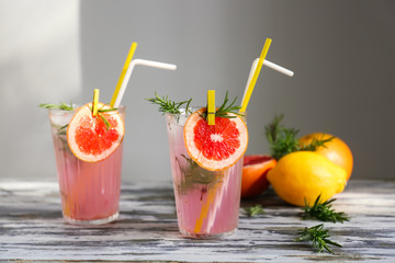 Fresh grapefruit cocktail with rosemary in glasses on wooden table