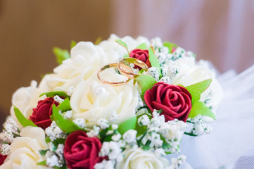 Wedding rings on a bouquet of red roses. Wedding Candles. Bouquet of the bride. Garter of the bride