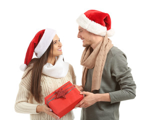 Cute young couple with Christmas gift on white background