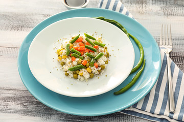 Plate with tasty boiled rice and vegetables on wooden table