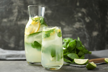 Glass and jug of fresh mojito on grey table