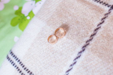 Wedding rings lie on bed. Golden rings. Two rings on bed. Couple of rings on white background.