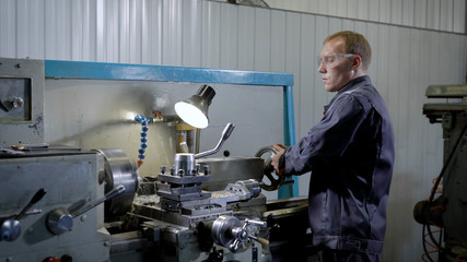 Industrial plant worker working at the lathe machine.