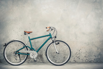 Retro bicycle with aged brown leather saddle from circa 90s front concrete wall background. Vintage...