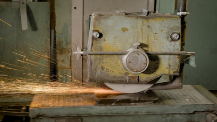 Fototapeta na wymiar grinding machine is whittling metal plate in a workshop, automatic equipment in a plant of production