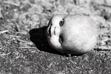 Demonic damned head of a doll in the dark room look at you.