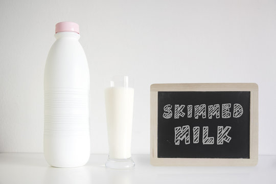 Natural fresh skimmed milk in a glass next to a bottle against a white background. Empty copy space for Editor's text.
