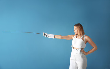 Young female fencer on color background