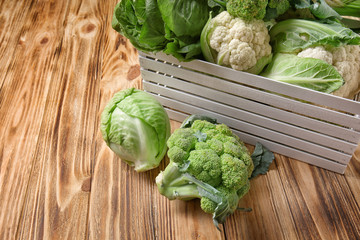 Crate with different types of cabbage on wooden background