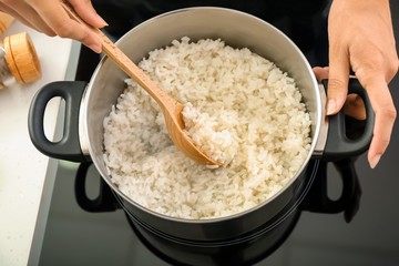Woman cooking rice in saucepan on stove
