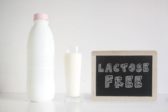 Natural lactosa free milk in a glass next to a bottle against a white background. Empty copy space for Editor's text.