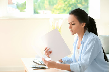 Young woman working with financial papers at table