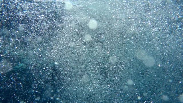 Bubbles rise from the depth to the surface in slow motion. They turbulize and dissolve in water. They pass close to the camera and propagate in defocus. 