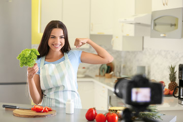 Young female food blogger recording video in kitchen