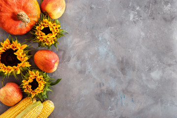A rustic autumn still life with pumpkin, apples and corn cobs