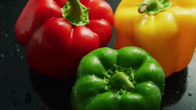 Closeup of shiny bell peppers of different colors with wet surface in water drops