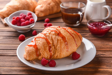 Tasty croissant with raspberry jam on plate