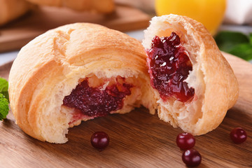 Tasty croissant with berry jam on wooden board, closeup