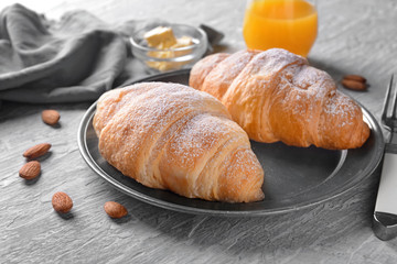 Tasty croissants with sugar powder on plate