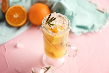 Glass cup of cold tasty cocktail on color table