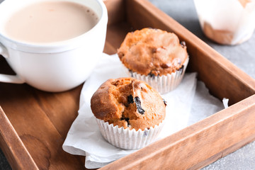 Tasty blueberry muffins with cup of coffee on wooden tray
