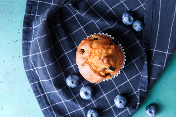 Tasty blueberry muffin on color table