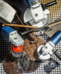 Set of professional angle grinders with different accessories over rusty and shiny metal plates