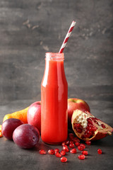 Bottle of tasty red smoothie and ingredients on grey table