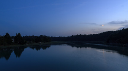 Beautiful dark blue nightscape landscape of the coastal river L'Arguenon after sunset with a new moon rising and reflection in the water near Saint-Malo in Brittany, France
