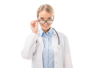 smiling young female doctor looking at camera over eyeglasses isolated on white