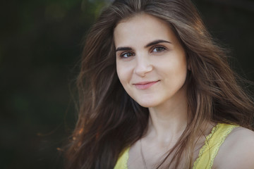 Young pretty fashionable girl in a yellow T-shirt is looking at a camera and smiling in an urban environment.