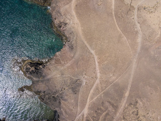 Vista aerea delle coste frastagliate e delle spiagge di Lanzarote, Spagna, Canarie. Strade e sentieri sterrati. Bagnanti in spiaggia e nell’Oceano Atlantico. Papagayo