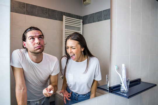 Couple in crisis fighting in the bathroom, angry girlfriend yelling at the boyfriend.