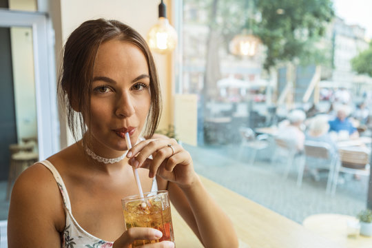 young brunette having ice tea at a caf&eacute; 