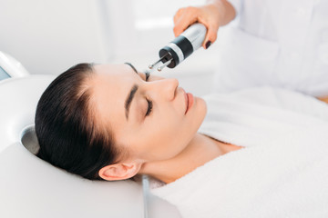 Obraz na płótnie Canvas Attractive woman getting facial microcurrent therapy in spa salon