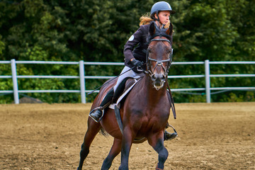 Young woman jockey in white black dress and black boots, takes part in equestrian competitions....